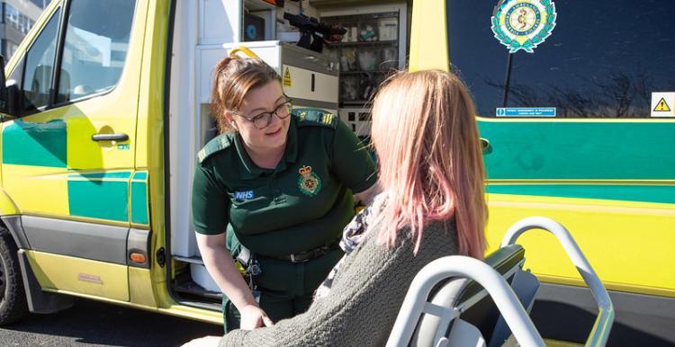 Wheelchair user speaking with a patient transport staff member. 